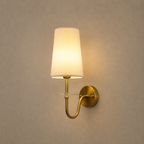 Wall-mounted lamp with a white shade and gold fixture on a beige wall.