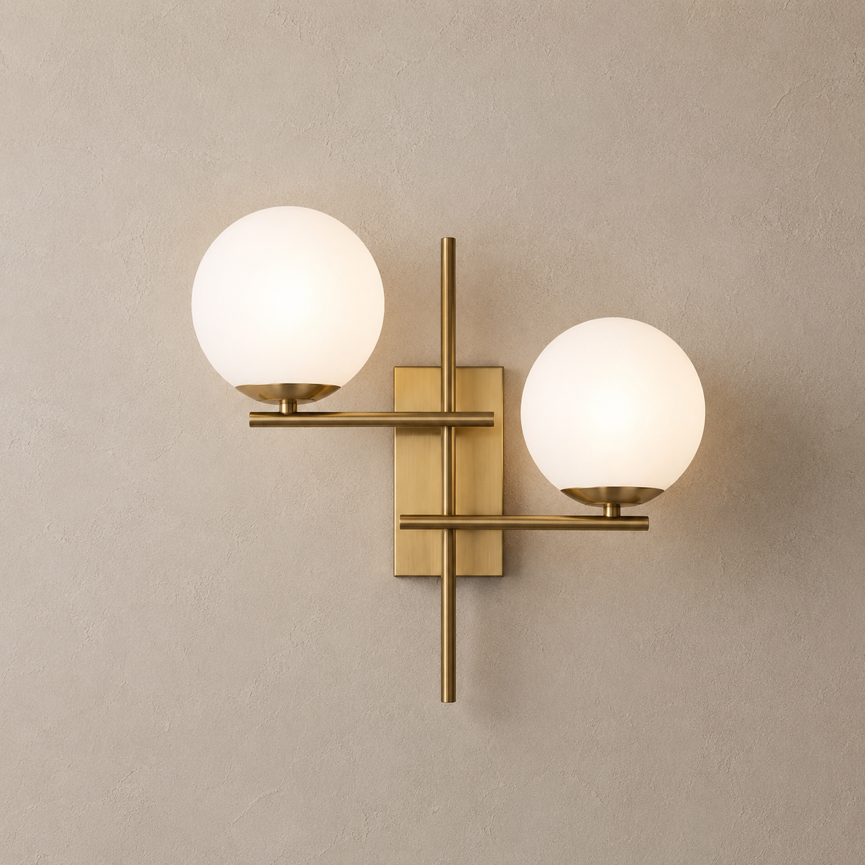 Wall-mounted lamp with two round glass shades and gold metal fixtures on a beige wall.