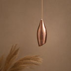Copper pendant light against a beige background with pampas grass