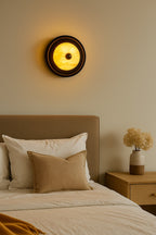 Bedroom with a wall sconce, bed, and nightstand with decorative items.