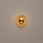 Gold circular light fixture on a beige wall