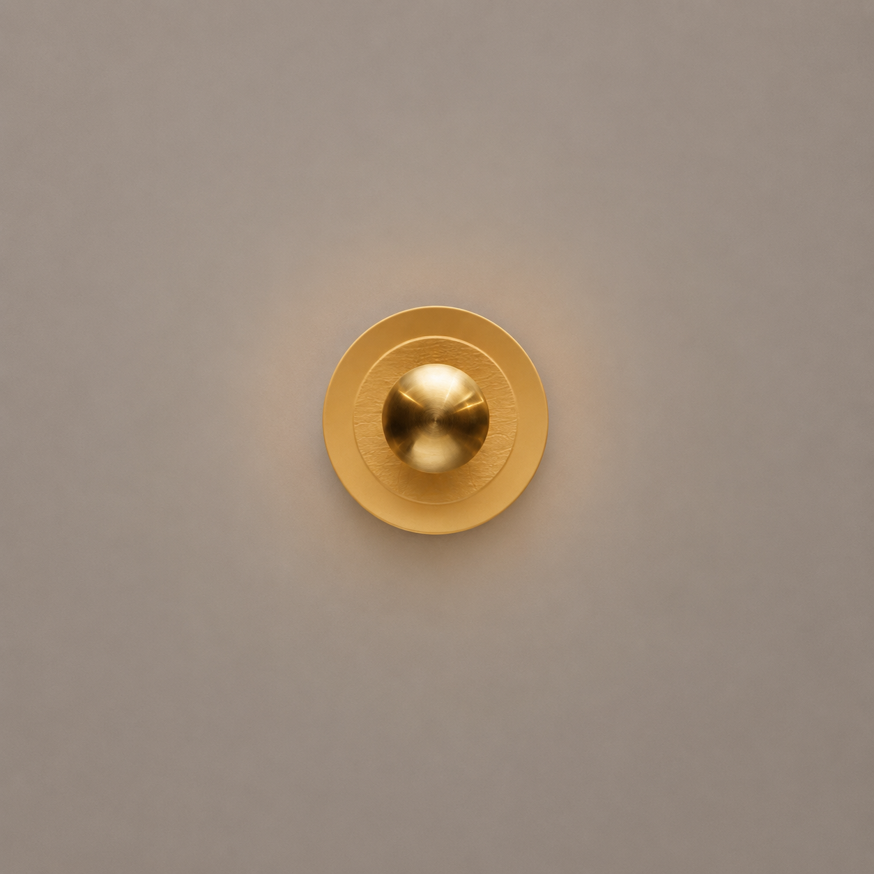 Gold circular light fixture on a beige wall