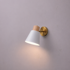 Wall-mounted light fixture with white shade and gold arm on a gray wall