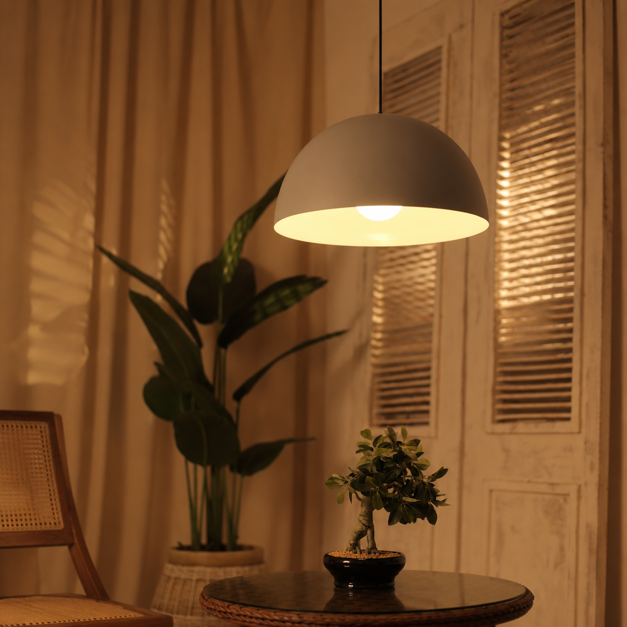 White pendant light hanging above a table with plants in a room setting