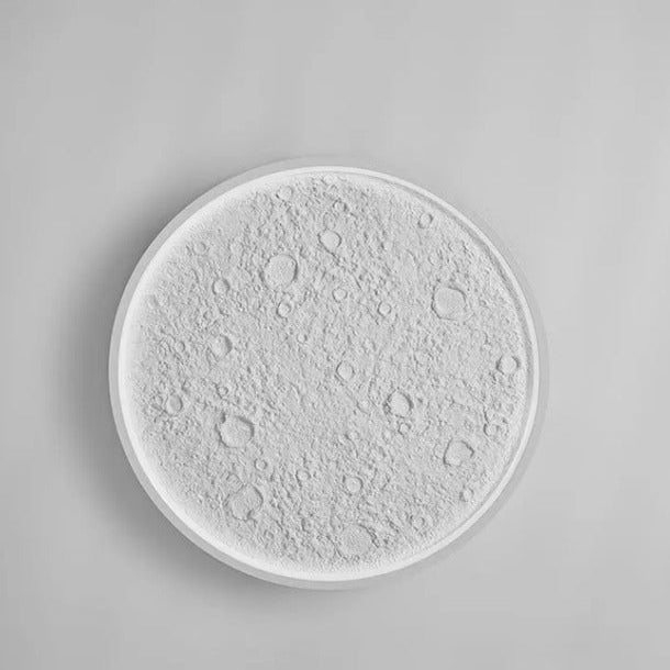 Round ceramic plate with moon surface design on a gray background