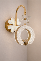 Decorative wall light fixture with gold and crystal design on a beige wall.