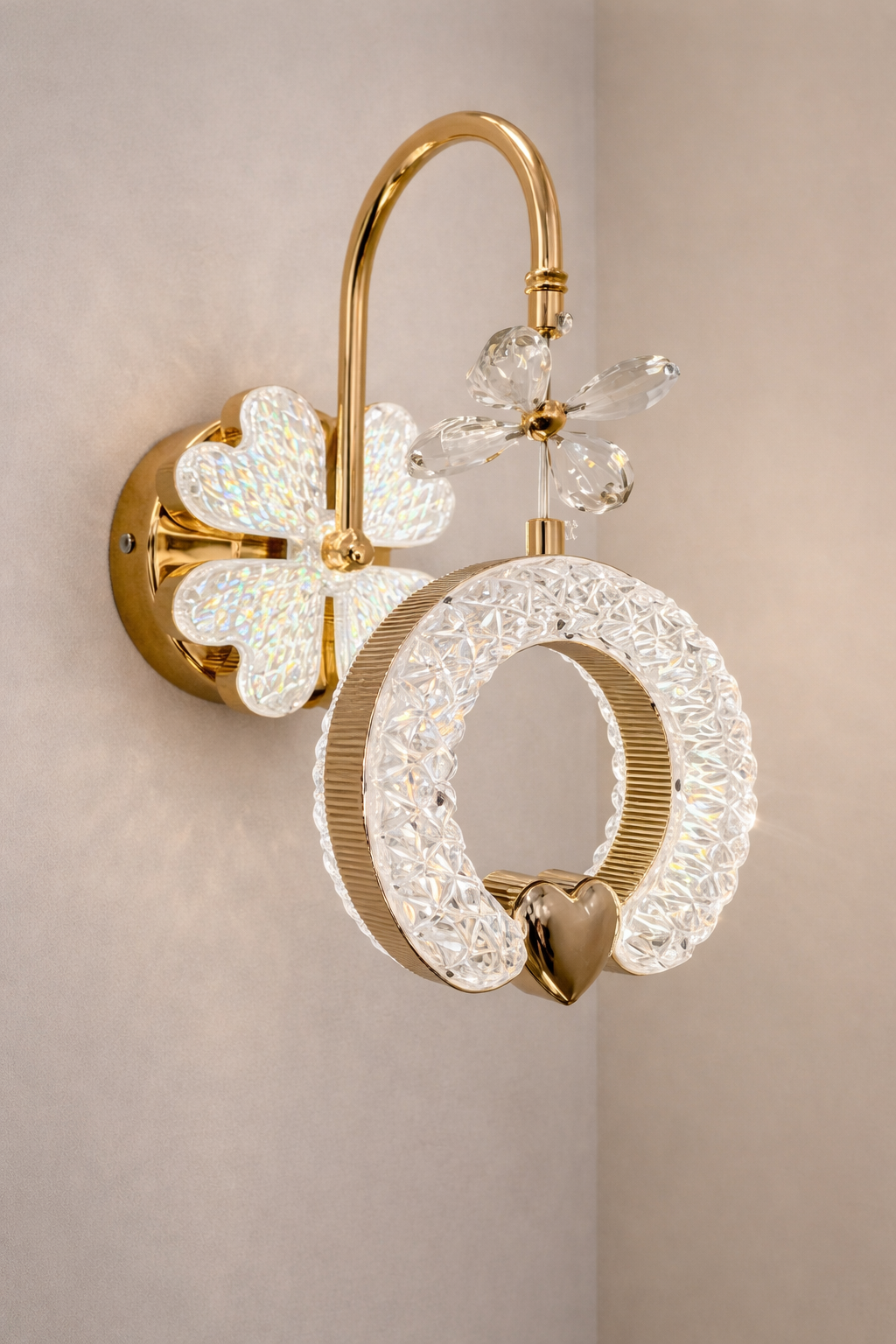 Decorative wall light fixture with gold and crystal design on a beige wall.